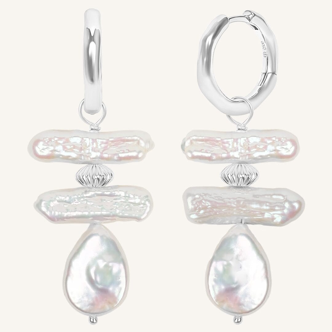 Pair of silver hoop earrings with teardrop-shaped pearls on a white background