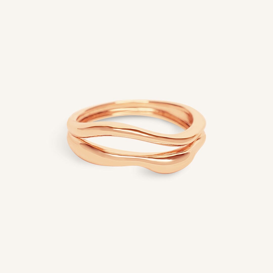 Rose gold ring with wavy design on a white background