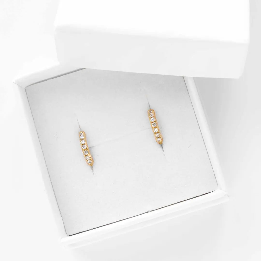 Small gold huggies, with cubic zirconias wrapped around, displayed in white box