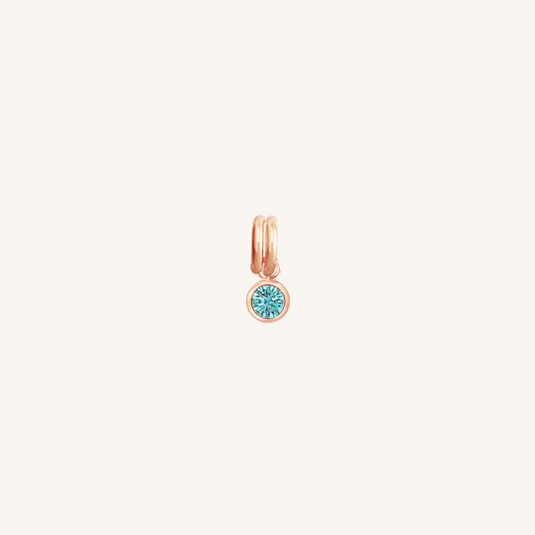 Round rose gold charm with bezel-set turquoise cubic zirconia representing the December birthstone