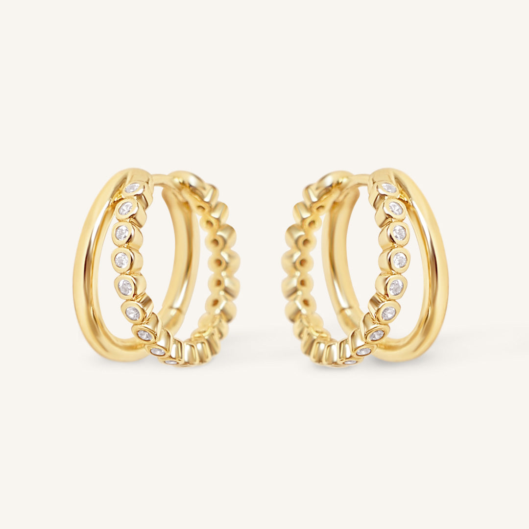 Gold hoop earrings with cubic zirconias on a white background