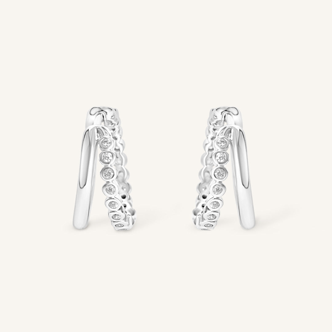 Pair of silver hoop earrings with small cubic zirconias on a white background