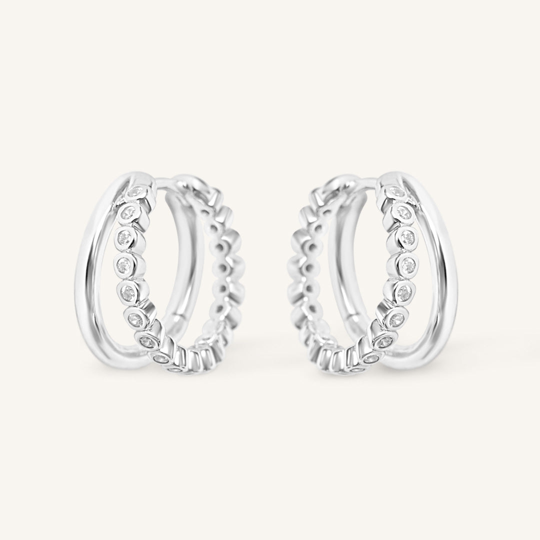 Pair of silver hoop earrings with cubic zirconias on a white background