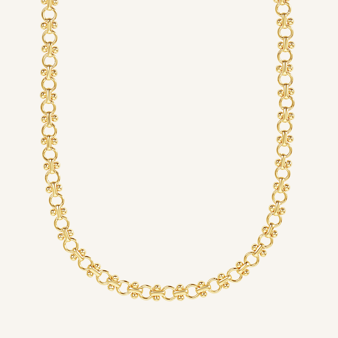 gold chain necklace inspired by Eiffel tower on plain background
