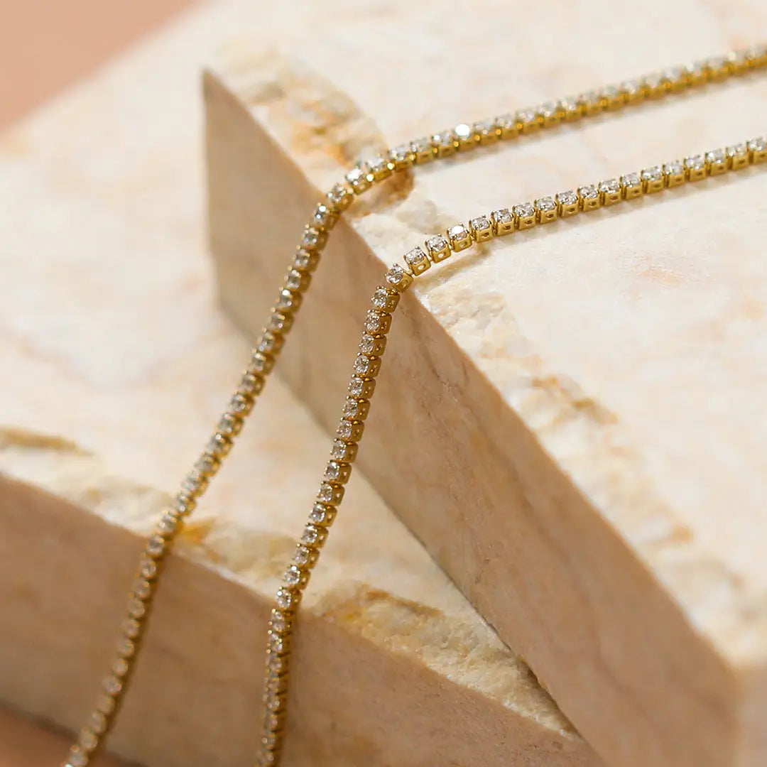 A tennis chain necklace with gold metal tone.