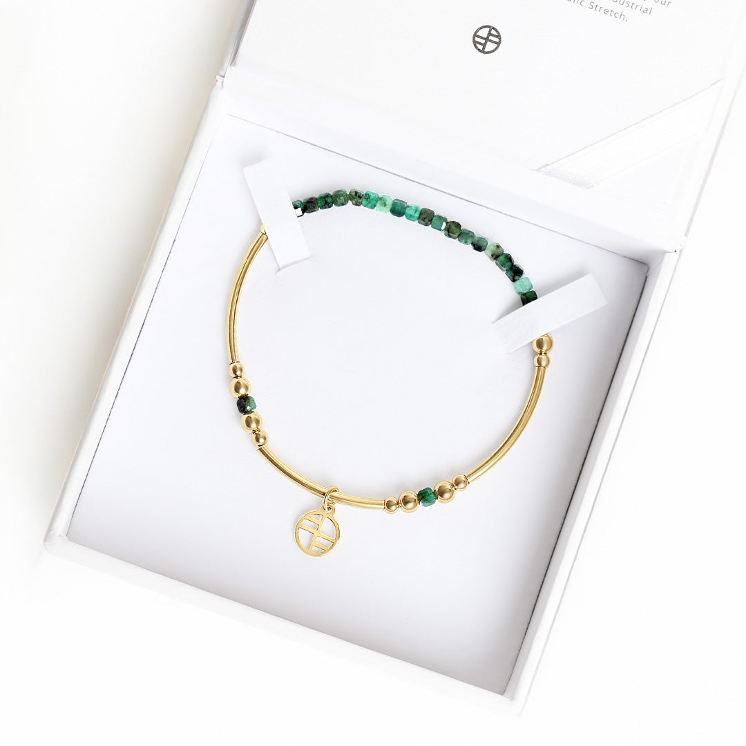 Gold bracelet with green beads in a white box