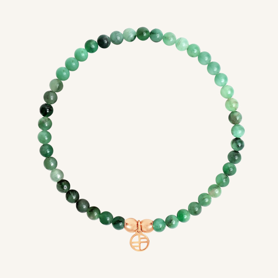 Green beaded bracelet with a rose gold charm on a white background