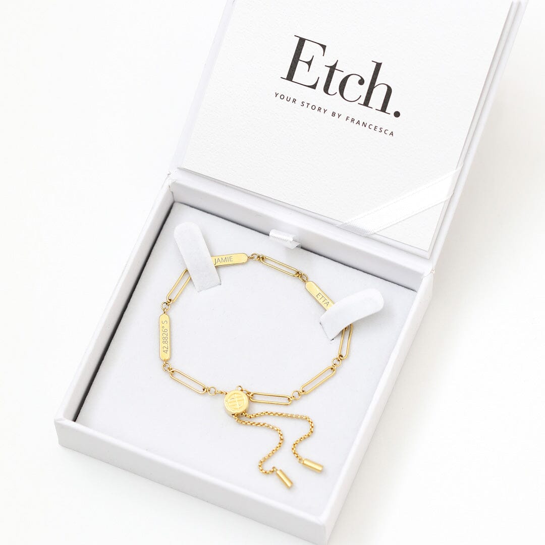 A gold Etch chain bracelet with three panels for engraving, featuring an adjustable fastening mechanism, displayed in a white box