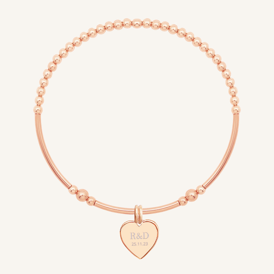 A rose bracelet with a beaded design and a heart-shaped charm, engraved with initials and a date