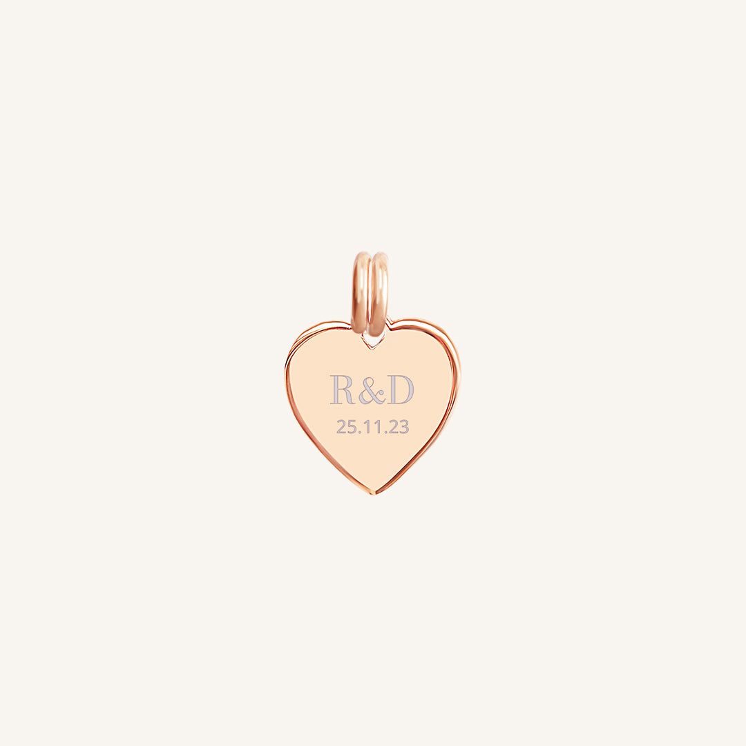 A rose heart-shaped charm with engraved initials and a date