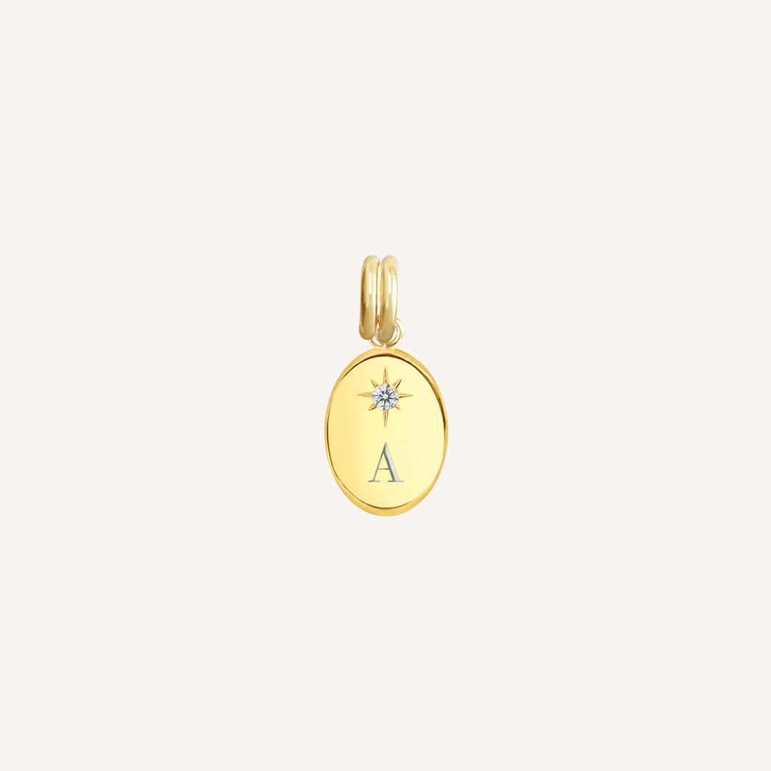 Gold pendant with 'A' initial on a light beige background
