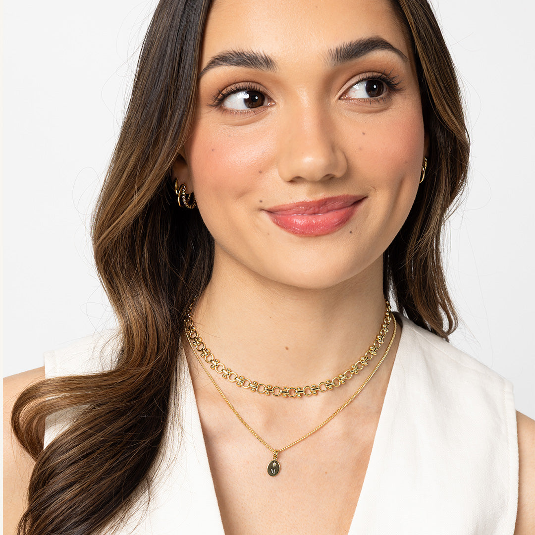Woman wearing a gold necklace and earrings on a white background