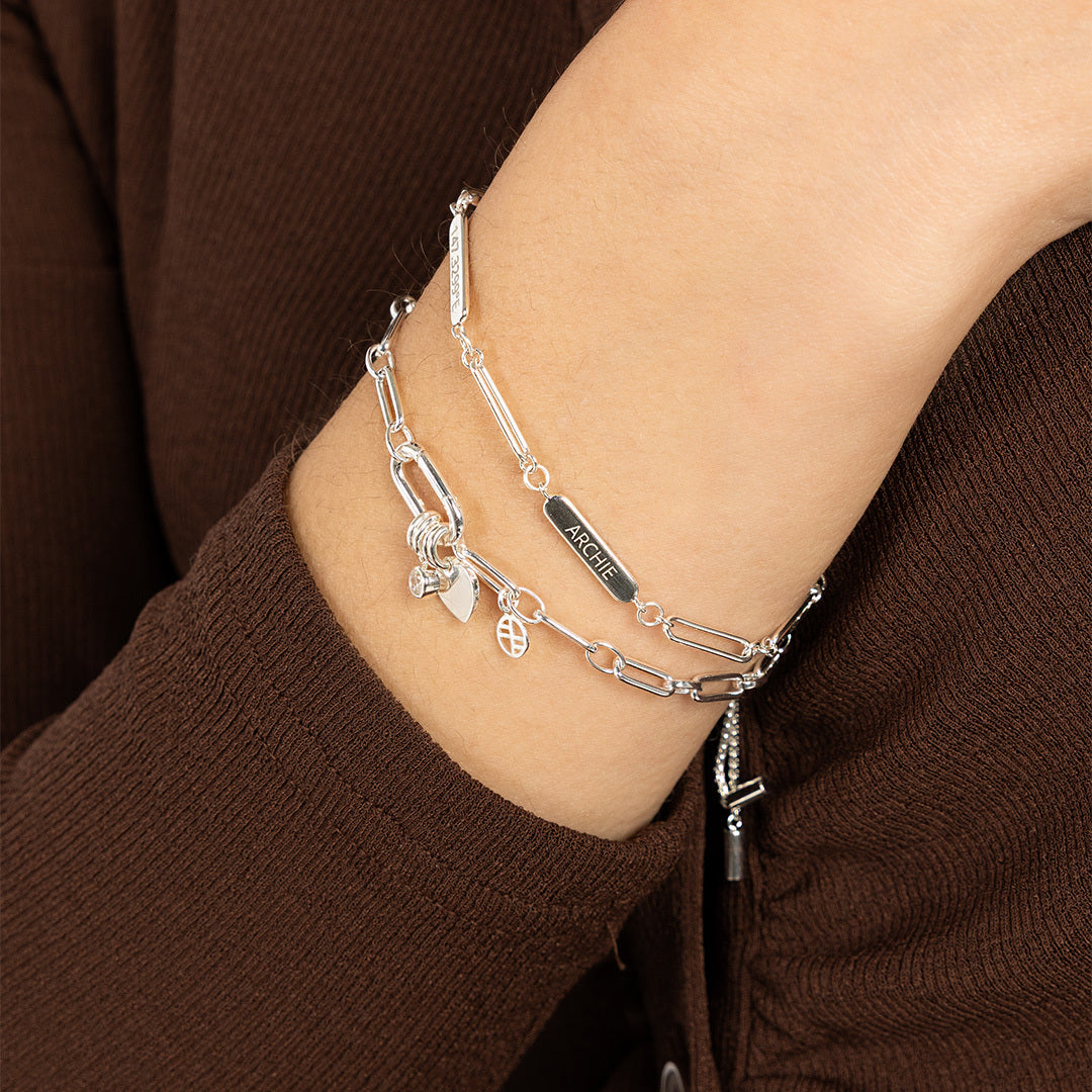 A silver Etch chain bracelet with three panels for engraving, worn on models wrist