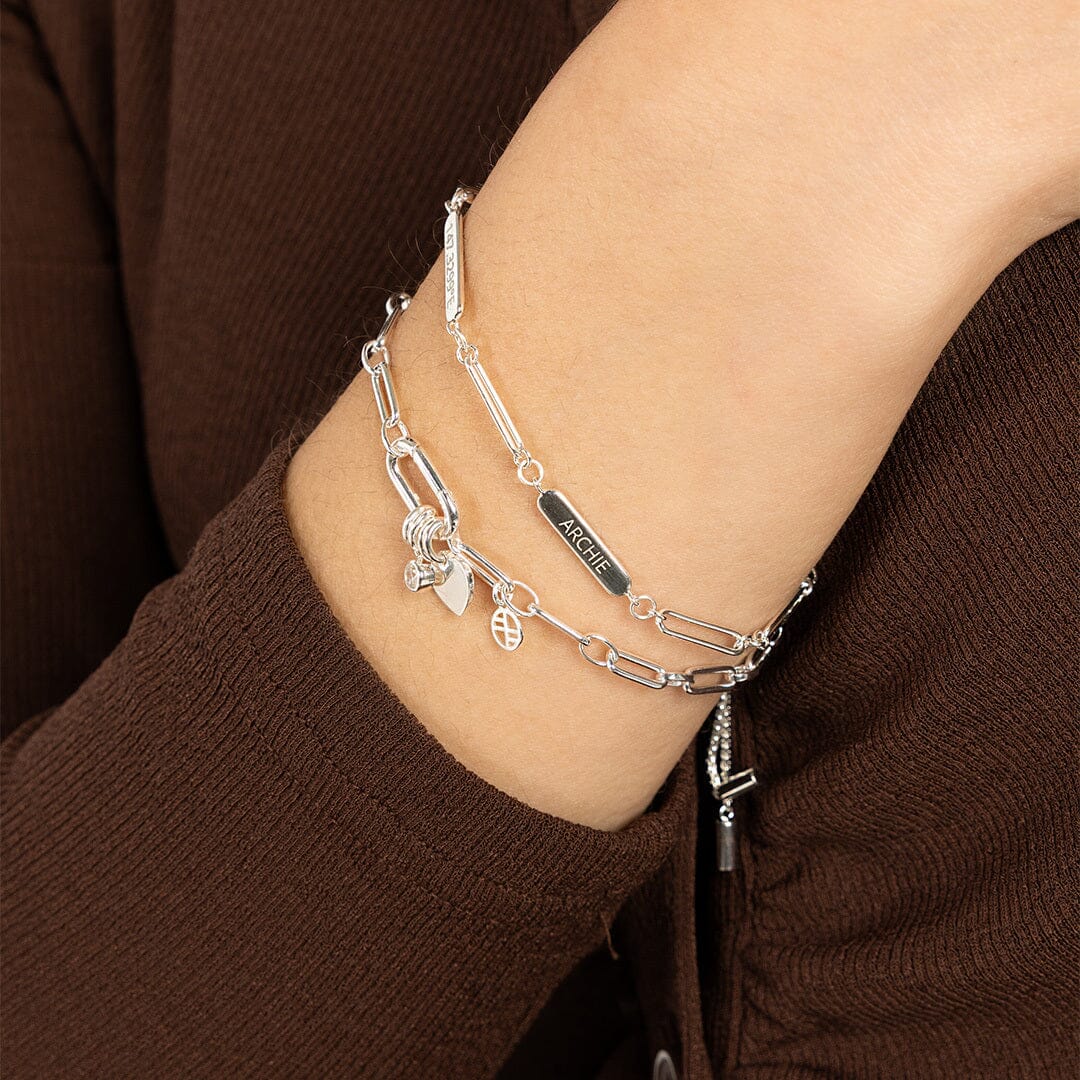 A silver Etch chain bracelet with three panels for engraving, worn on models wrist