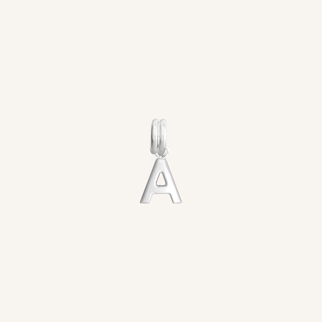 A silver charm in the shape of the letter A with a white background.