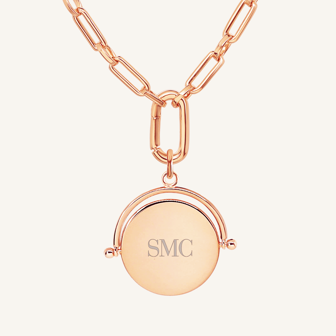 A rose-coloured, engraved pendant with, featuring a spinning mechanism, on chain