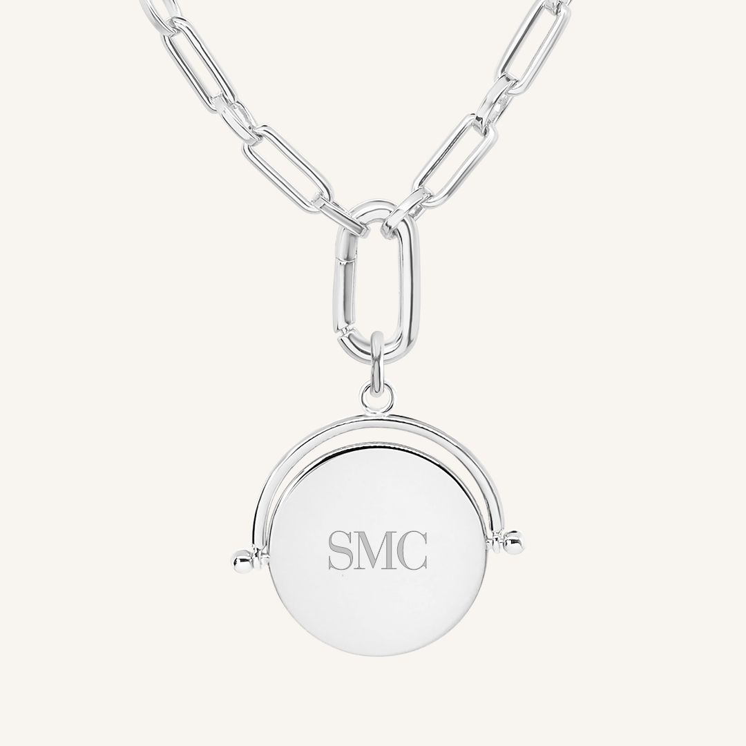 A silver-coloured, engraved pendant with, featuring a spinning mechanism, on chain