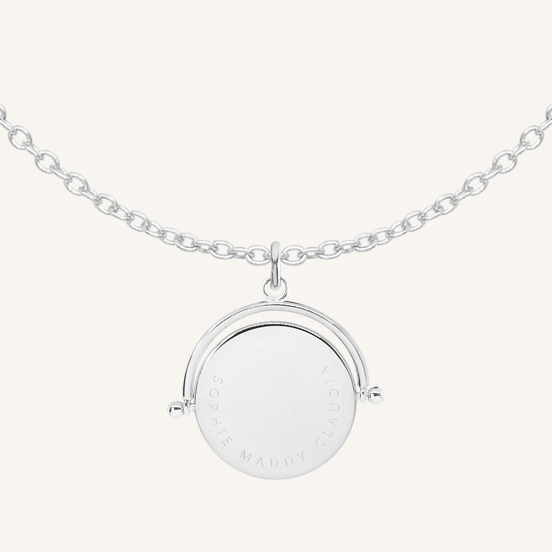 A silver-coloured, engraved pendant with, featuring a spinning mechanism, on chain