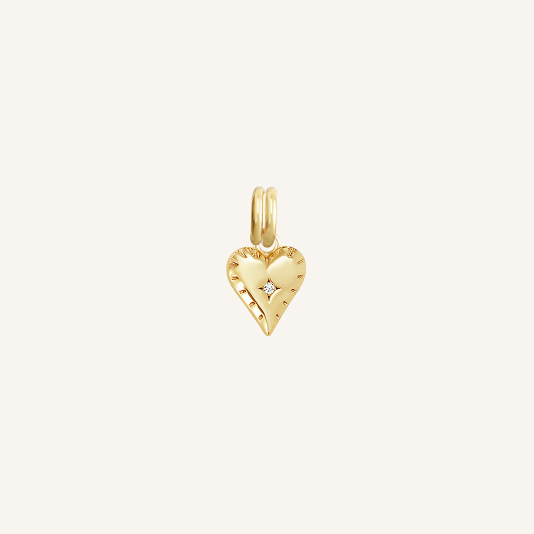 A delicate heart-shaped charm in gold metal tone, designed to be attached to a bracelet or necklace