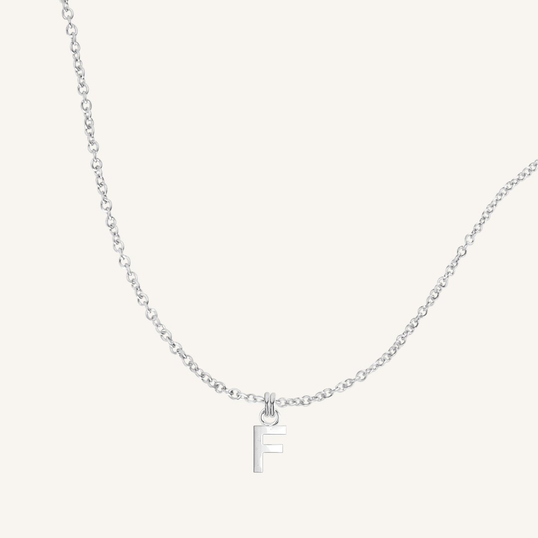 Silver necklace with a 'F' pendant on a light gray background