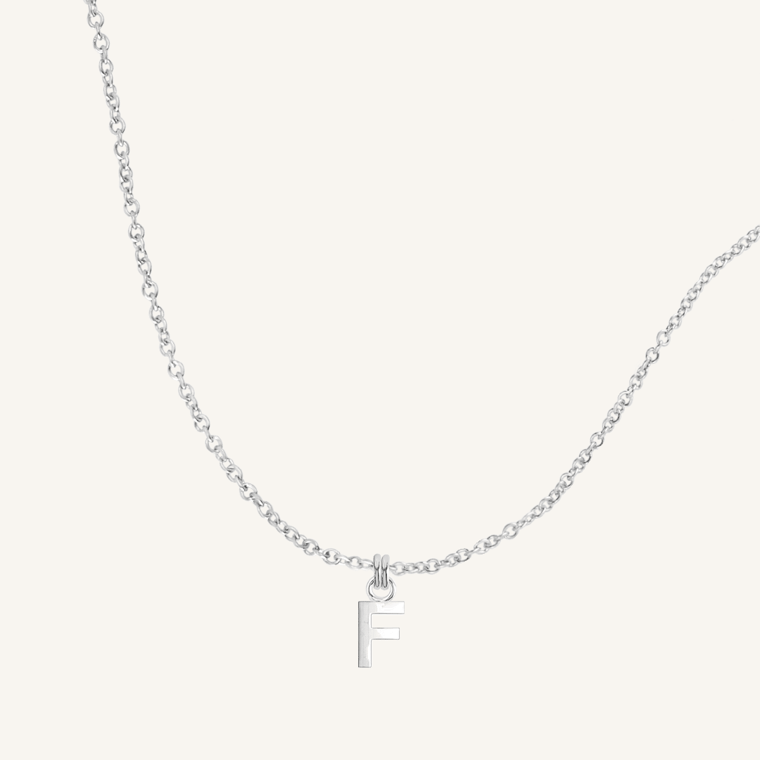 Silver necklace with a 'F' pendant on a light gray background