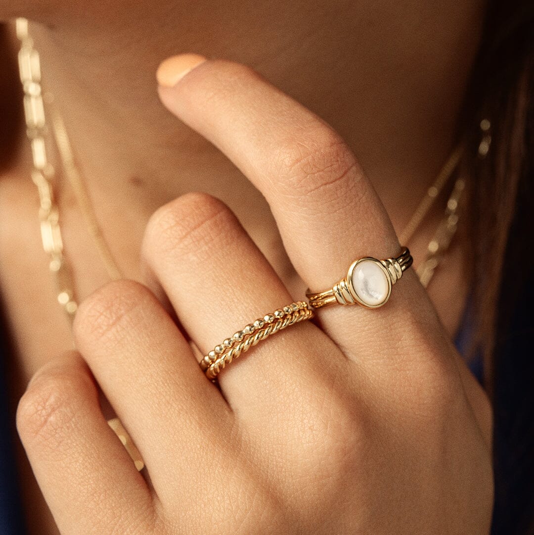 Gold ring with a Mother of Pearl stone close up on finger