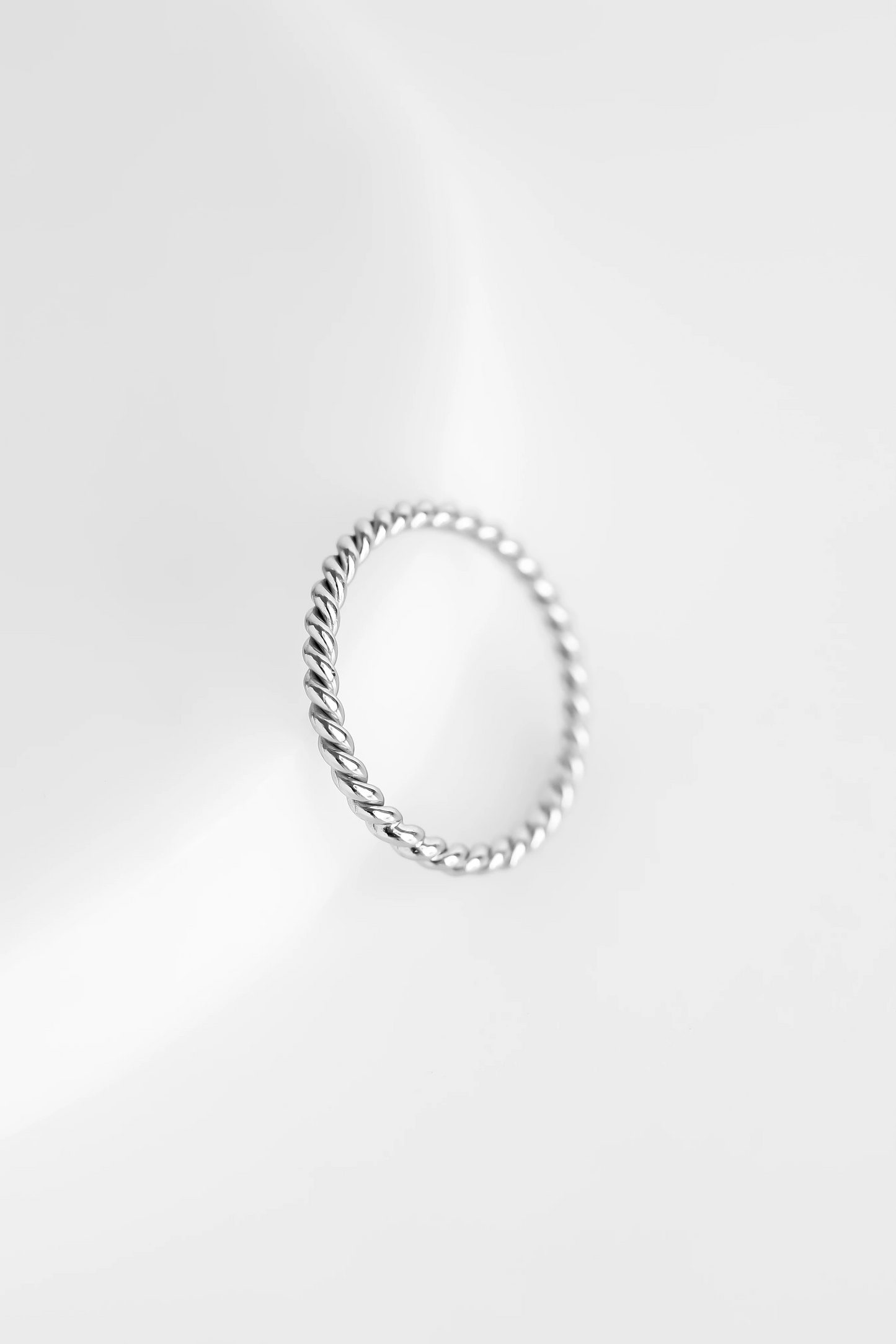 A silver-coloured stacking ring with a twisted design, displayed against a white background.