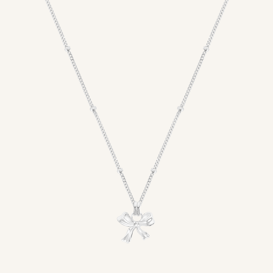 A silver-colored necklace featuring a bow-shaped charm attached to a hoop.