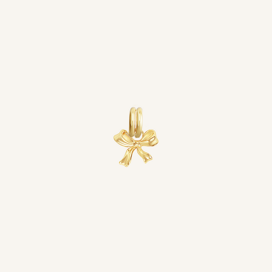 A small gold bow charm with a loop on top for attachment, displayed on a white background.