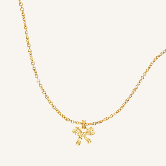 A gold-tone charm necklace with a bow pendant.
