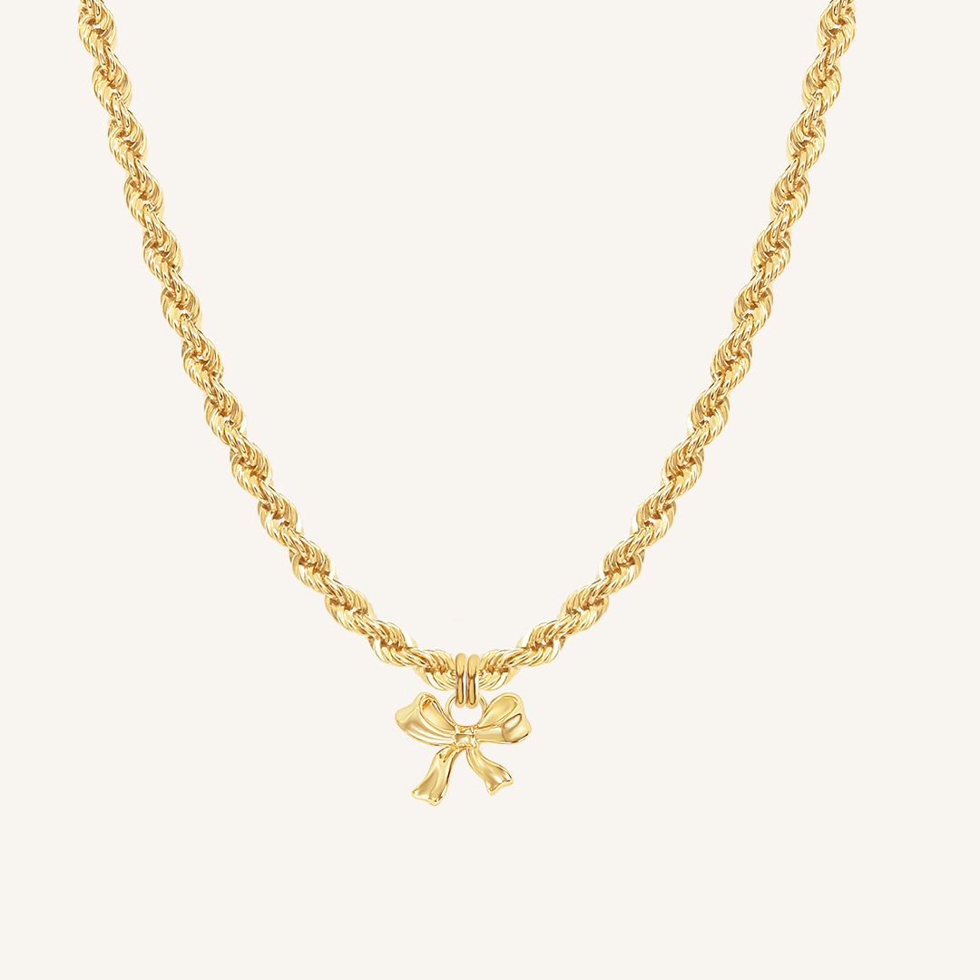 A gold-tone charm necklace with a bow pendant.