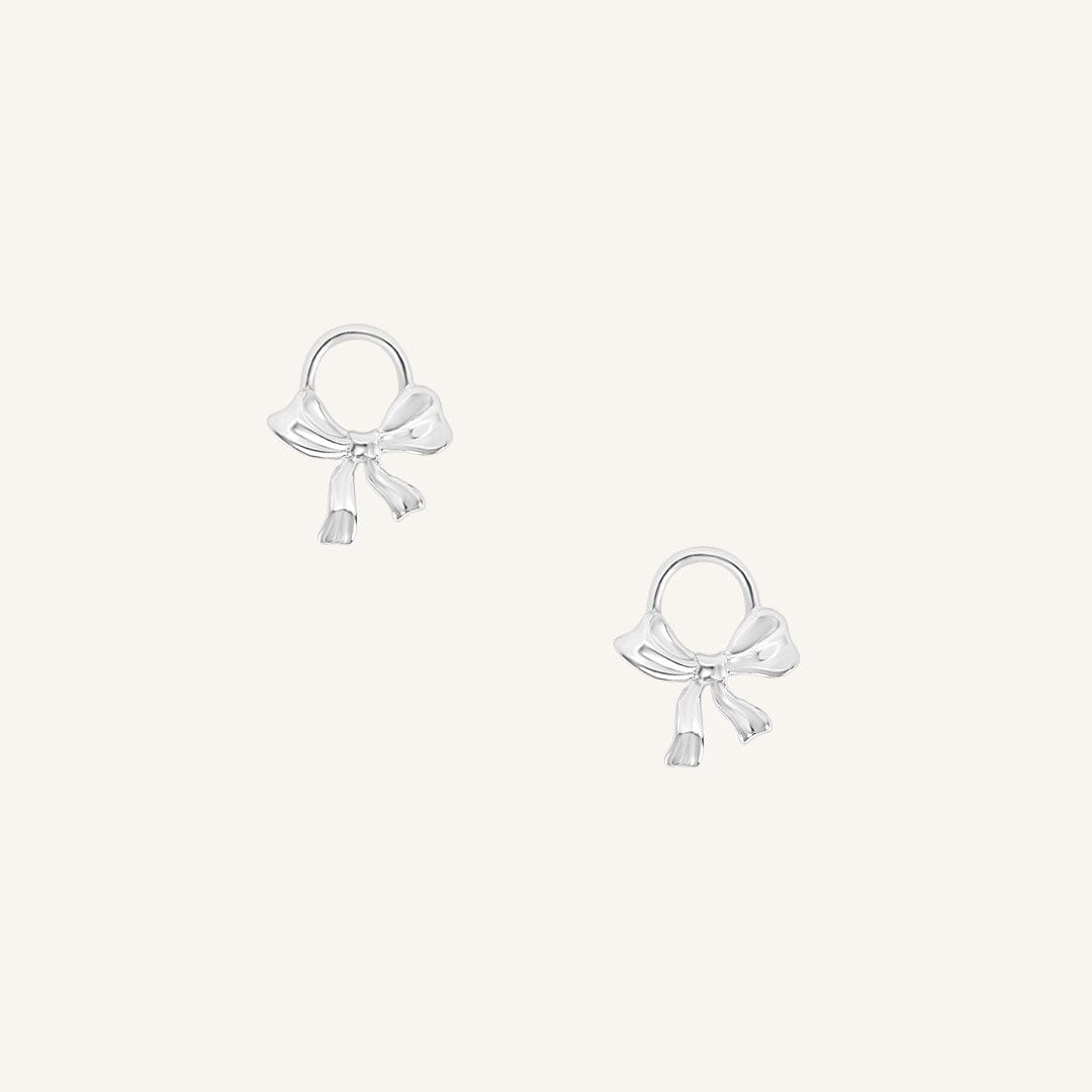 A set of two silver hoop charms with a bow design.