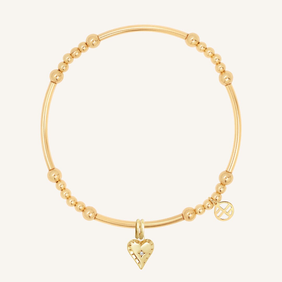 A gold-colored charm bracelet featuring a heart-shaped charm and small bead details.
