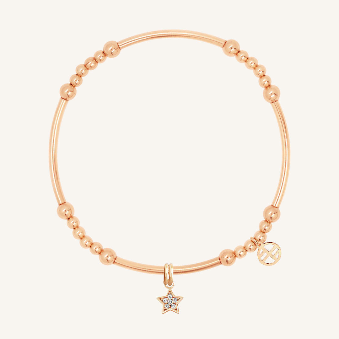 A rose gold-coloured bracelet with a luck star charm and small bead details.