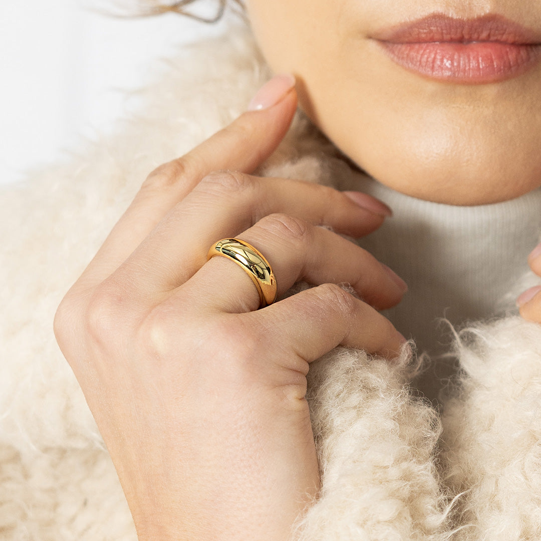 Close-up of a hand wearing a gold ring with a soft background