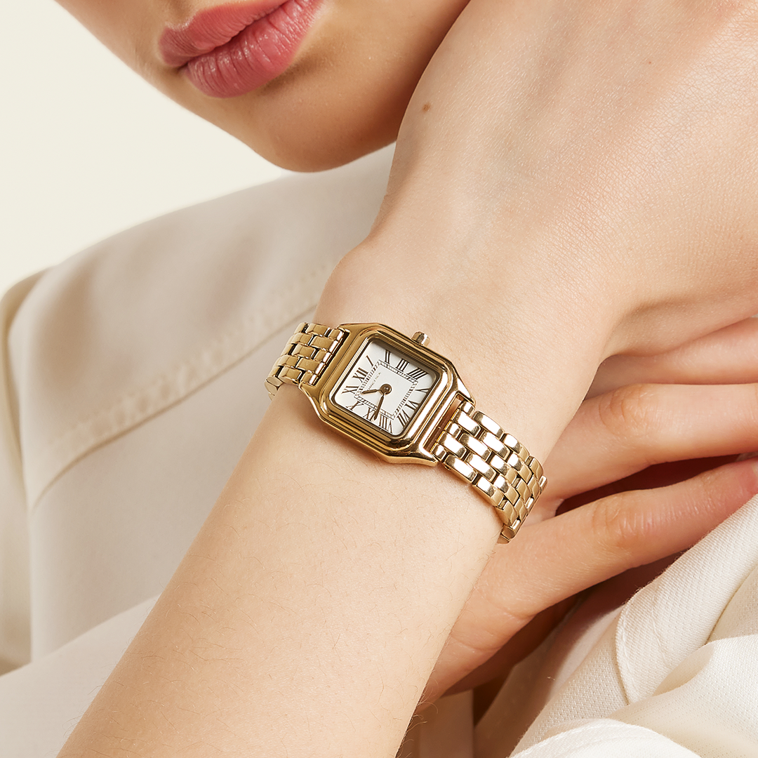 A gold-toned Louis Watch with a link bracelet and a square face featuring Roman numerals worn on the wrist