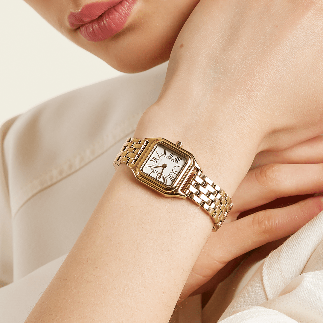 A gold-toned Louis Watch with a link bracelet and a square face featuring Roman numerals worn on the wrist