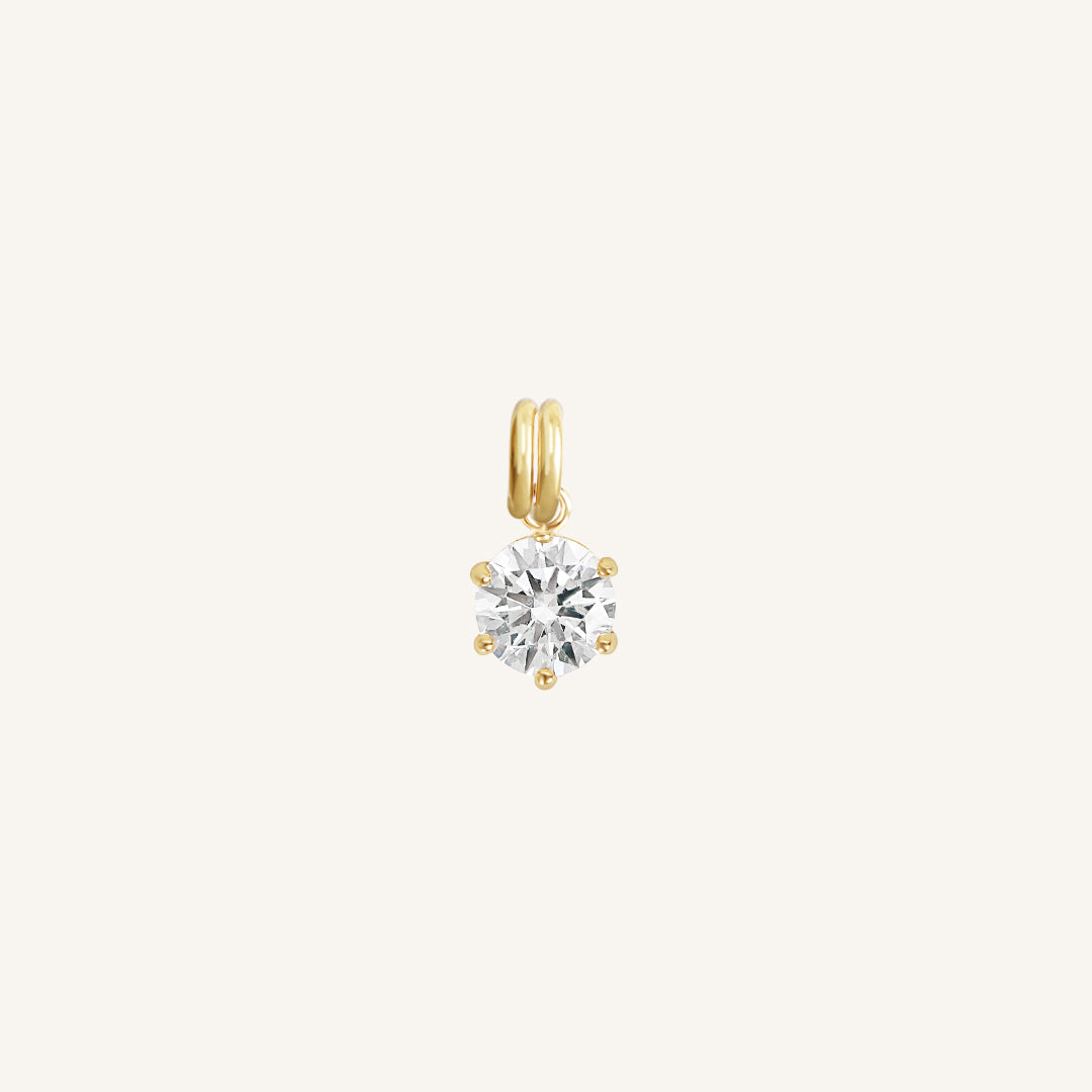 A round gold cubic zirconia charm on white background