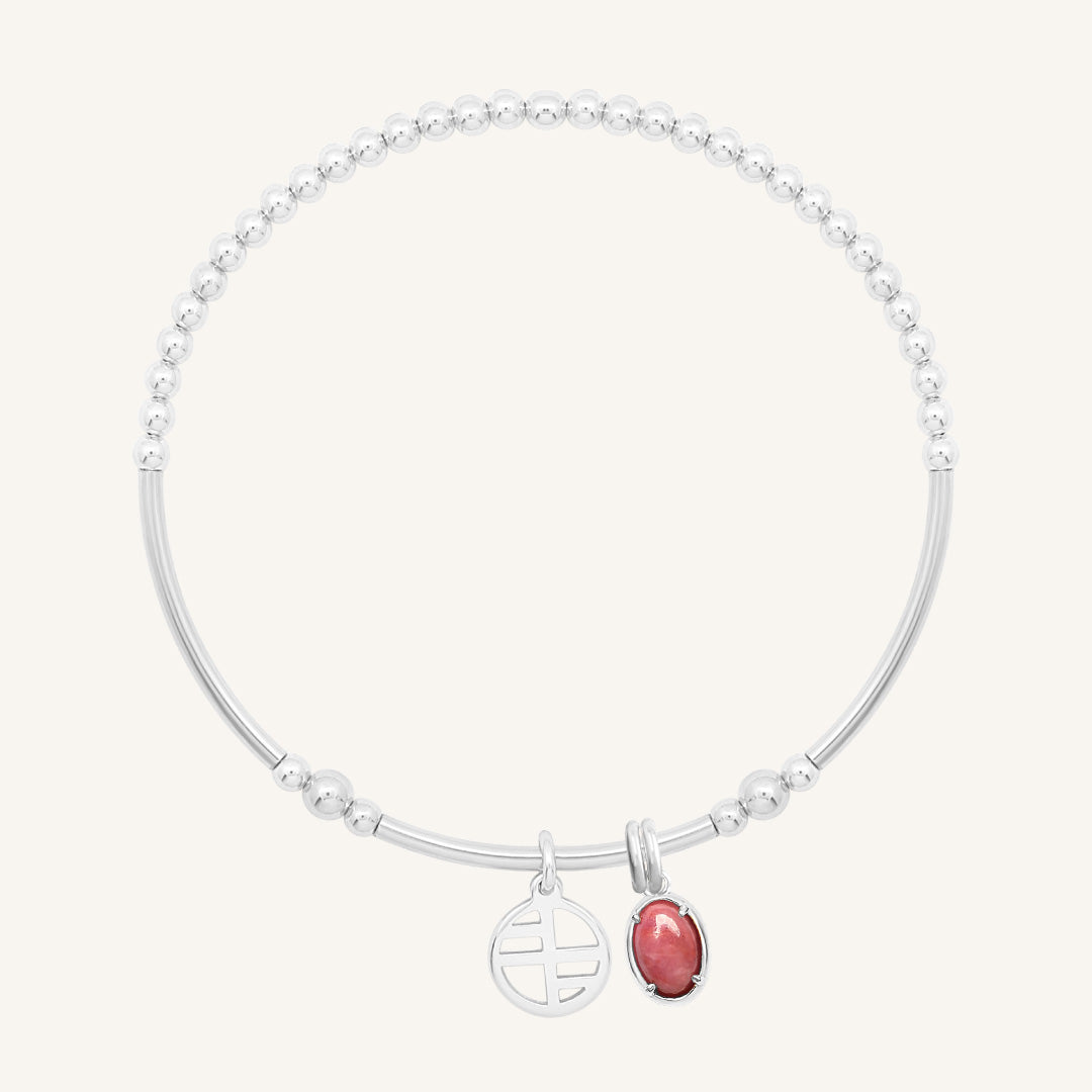 Silver bracelet with a red charm on a white background