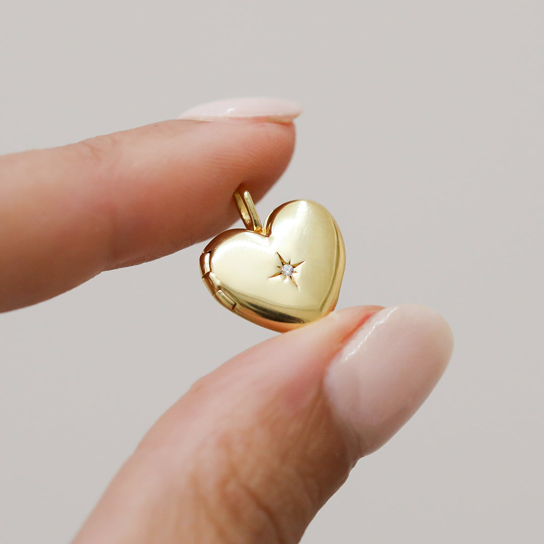A gold heart-shaped photo locket held up close closed
