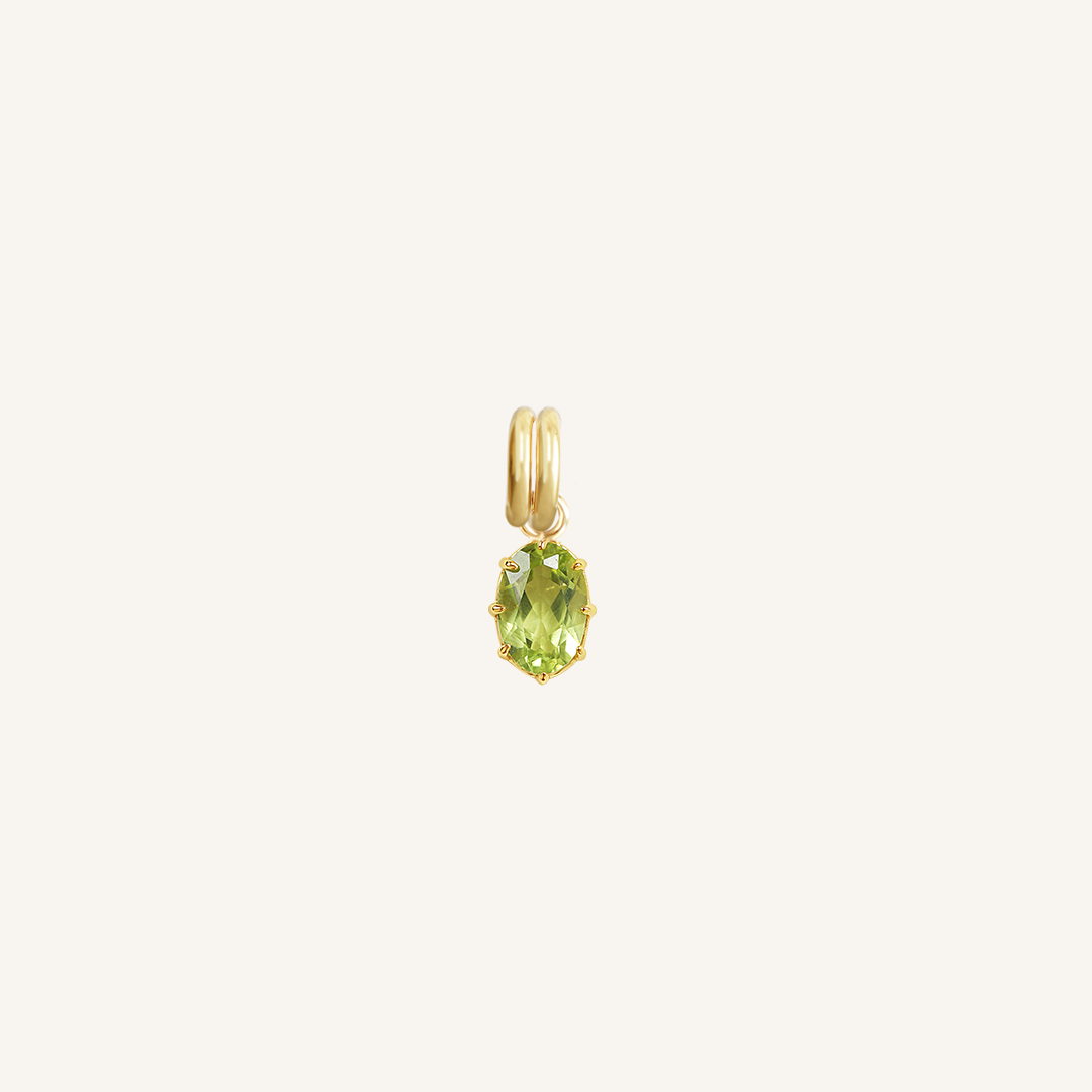 A gold charm with an olive green cubic zirconia, isolated on a white background.