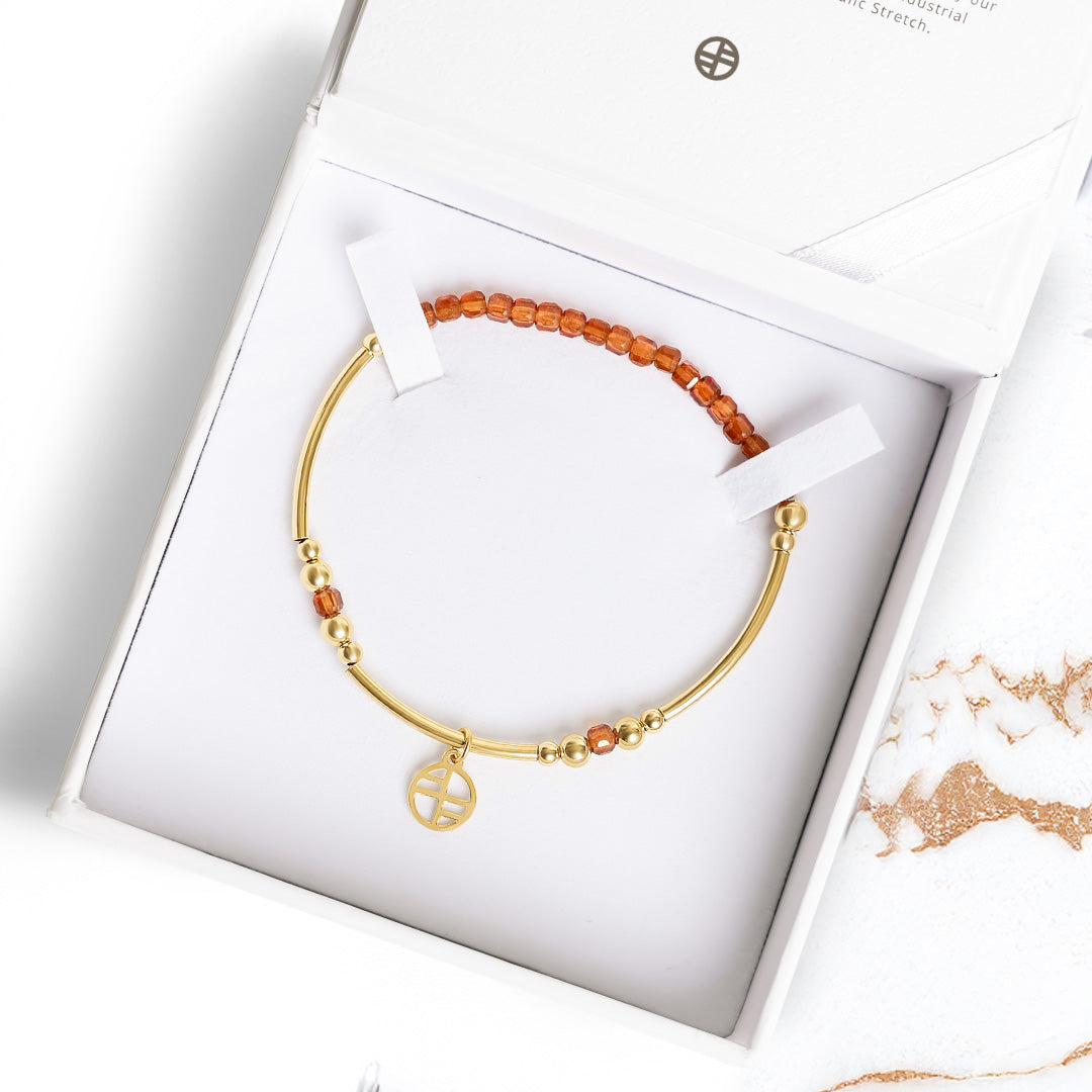 Gold bracelet with orange beads in a white jewelry box