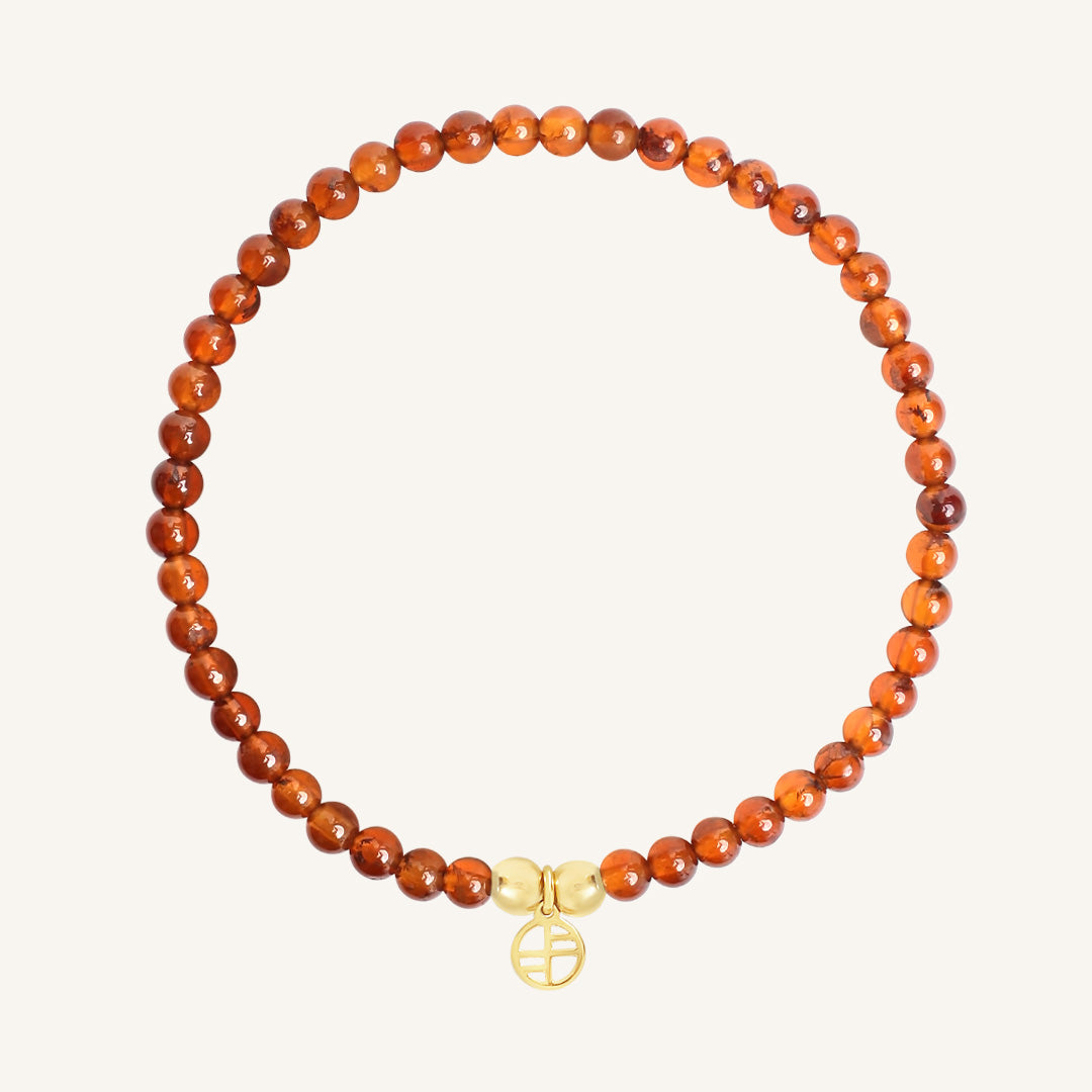 Bracelet with orange beads and a gold charm on a white background