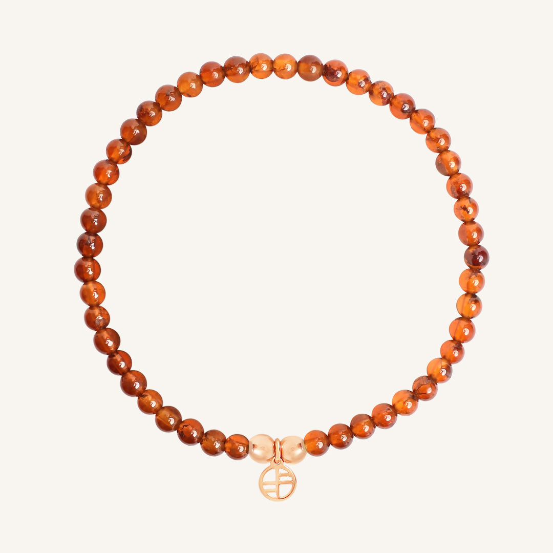 Orange beaded bracelet with a gold Francesca charm on a white background