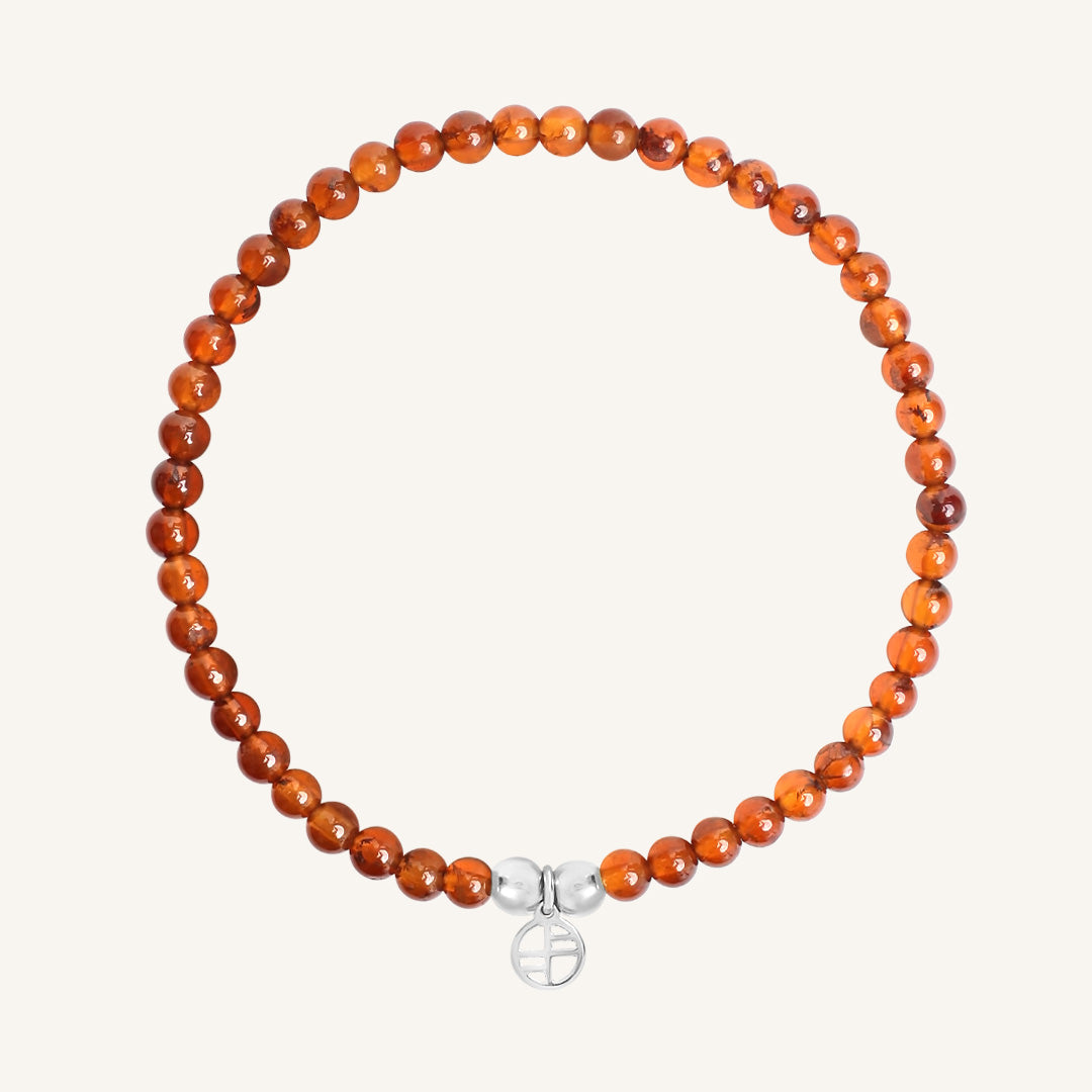 Orange beaded bracelet with a silver charm on a white background