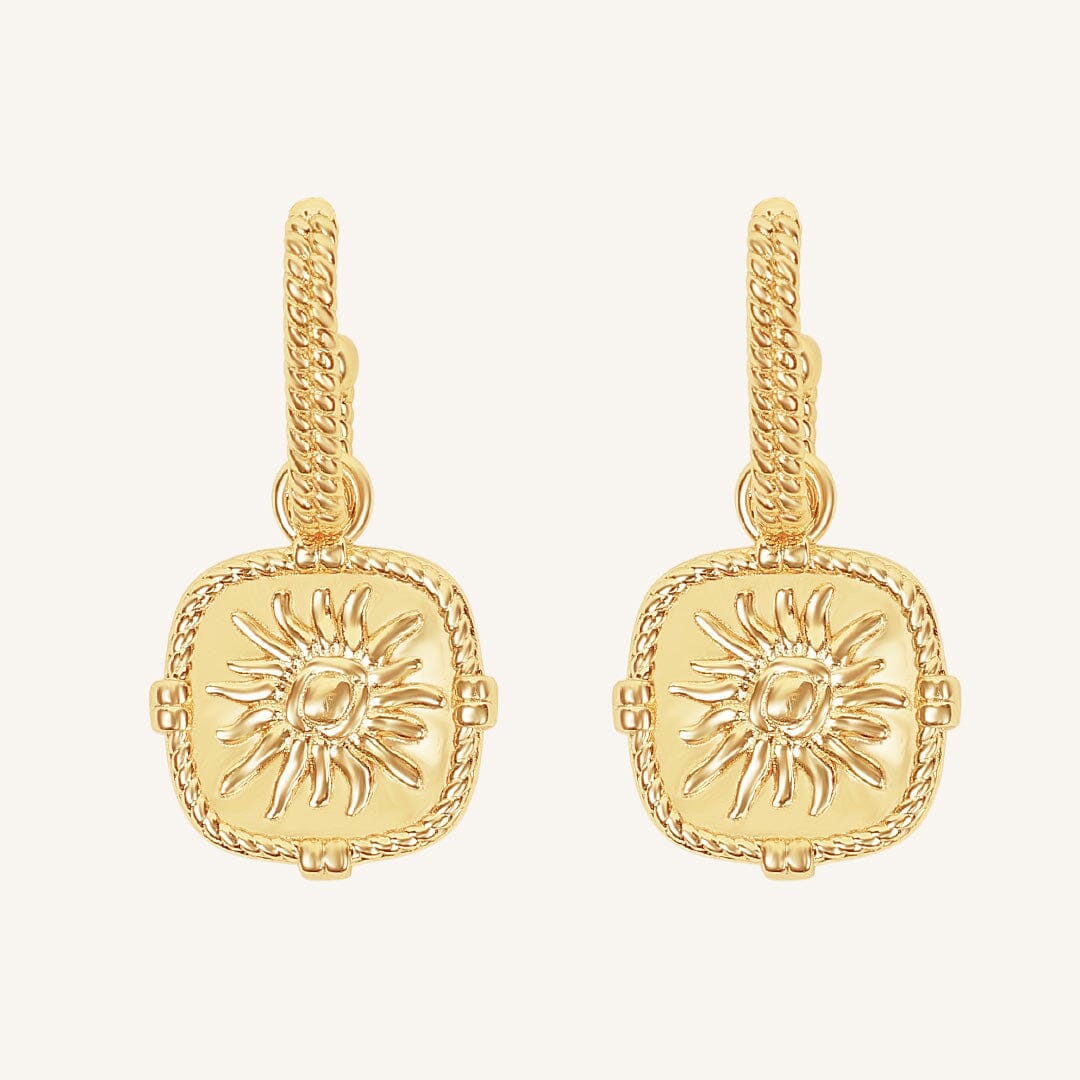 Gold earrings with sun design on a white background