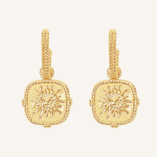 Gold earrings with sun design on a white background