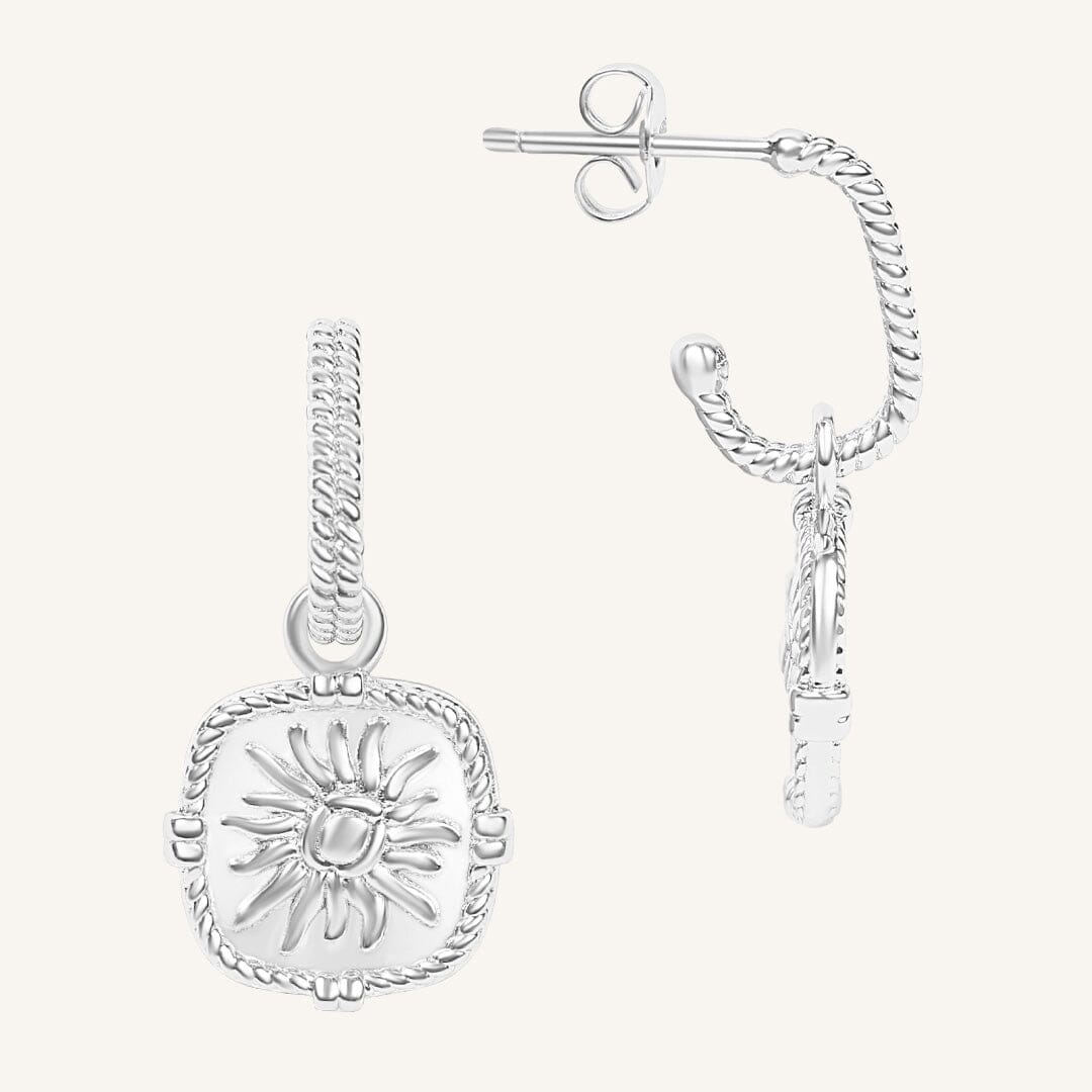 Silver sun-shaped earring on a white background