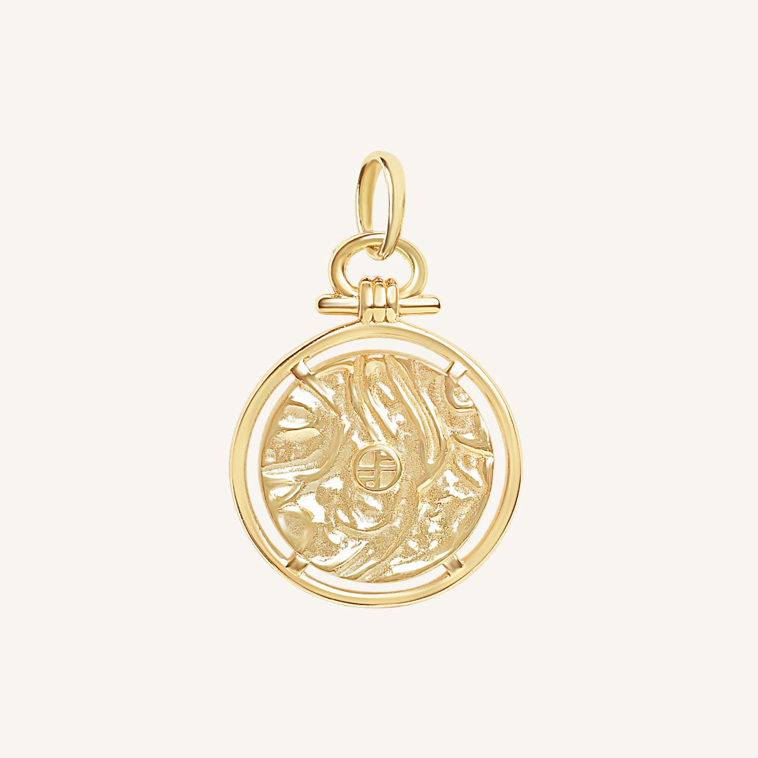 Gold pendant with intricate design on a light beige background