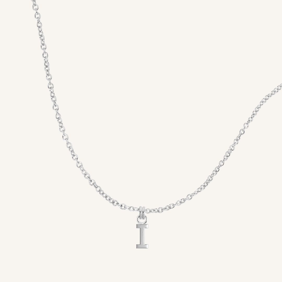 Silver necklace with a 'I' pendant on a light gray background